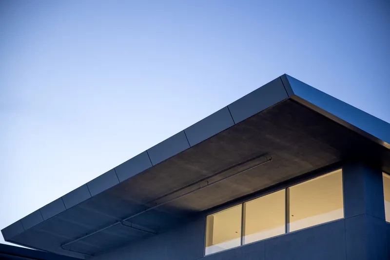 Casa moderna ao entardecer, com a luz acesa nas janelas